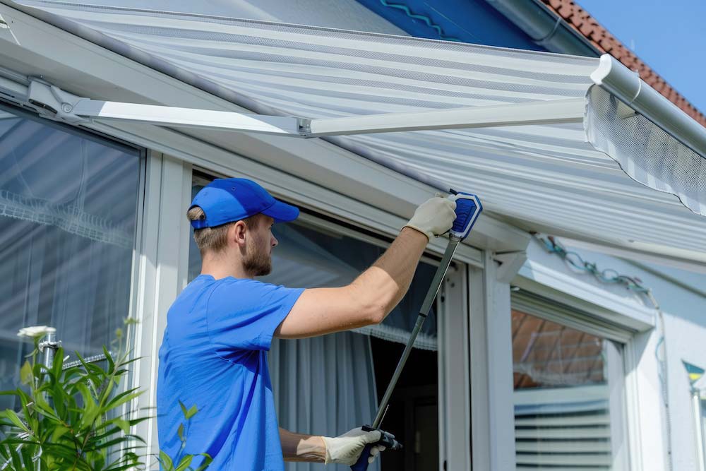 Homeowner cleaning patio sun shade fabric showing proper maintenance technique for longevity
